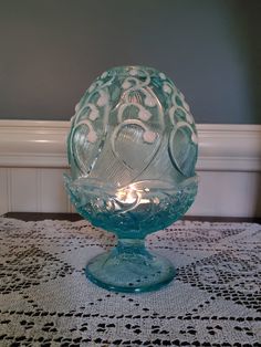 a glass bowl sitting on top of a table next to a doily covered table