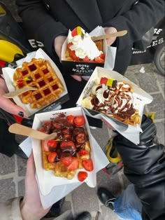 four waffles with toppings in paper containers