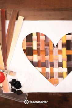 a paper heart cut out on top of a piece of wood next to other crafting supplies