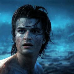 a young man with wet hair standing in the water looking off into the distance at night