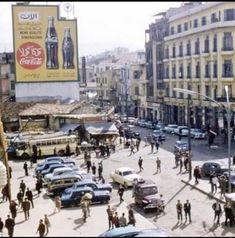 a busy city street filled with lots of cars and people walking on the side of it