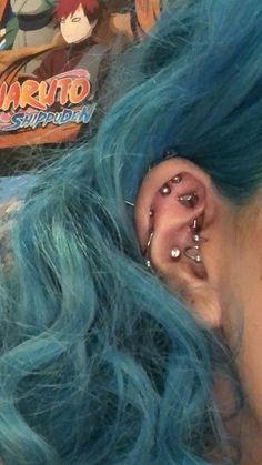 a close up of a person with blue hair and piercings on their ears wearing ear rings