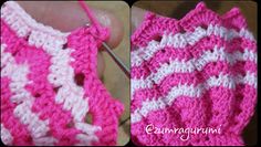 crocheted pink and white bag being worked on by someone using the knitting needle