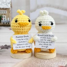 two small crocheted chickens holding signs that say good luck and little ducky