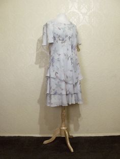 This is a very pretty 2 piece sleeveless long layered dress with matching long sheer chiffon jacket by r&m richards. still in brand new condition. it is a size 8. please go by the measurements below for proper fit. very elegant pretty women look. perfect for a garden party or summer wedding. the dress has a modest scoop neckline with a small keyhole button back. the dress is made of a pastel light sage green floral print crepe chiffon. the flowers are very light pastels of pinks and periwink Spring A-line Dress For Mother Of The Bride, Summer A-line Dress For Mother Of The Bride, Fitted Summer Dress With Overlay, Spring Short Sleeve Dress With Overlay, Spring Dress With Short Sleeves And Overlay, Spring Dresses With Overlay And Short Sleeves, Flowy Spring Dress With Overlay, Spring Knee-length Dress For Mother Of The Bride, Knee-length Spring Dress For Mother Of The Bride