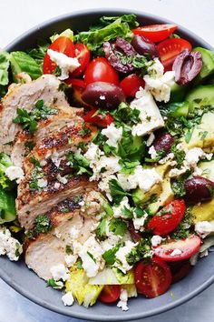 a salad with meat, tomatoes, lettuce and feta cheese in a bowl