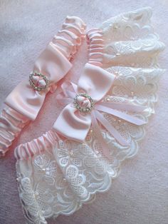 two pink garters with bows and pearls on them