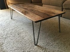 a wooden table sitting on top of a carpeted floor next to a brown couch