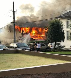 two men standing in front of a house on fire