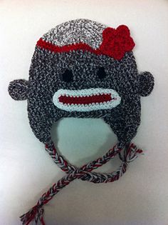 a knitted monkey hat with a red bow