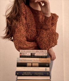 a woman sitting on top of a stack of books