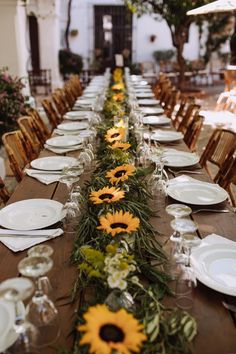 the long table is set with sunflowers and greenery