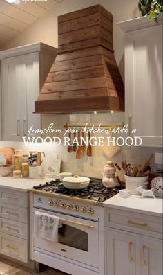 a kitchen with white cabinets and wood range hood