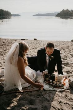 a bride and groom on the beach getting ready to cut their wedding cake