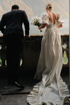 a man and woman standing next to each other in front of a body of water