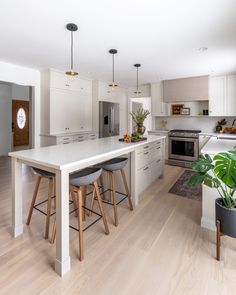 a kitchen with white cabinets and wooden stools in front of an island countertop