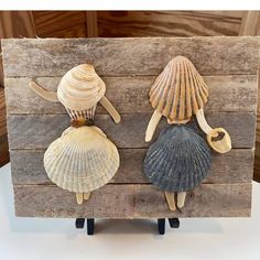 three seashells are sitting on top of a piece of wood