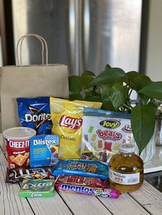 a table topped with lots of different types of snacks and drinks next to a potted plant