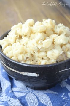 a black bowl filled with macaroni and cheese on top of a blue towel