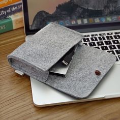 an open laptop computer sitting on top of a wooden desk next to a gray felt case