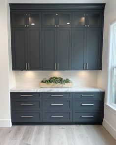 a kitchen with gray cabinets and marble counter tops