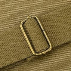 a belt with a metal buckle is shown in close up on a tan cloth background