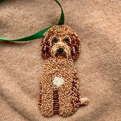 a beaded dog ornament hanging from a green ribbon on a brown shirt