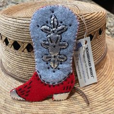 a straw hat with a blue and red boot on it next to a tag that says,