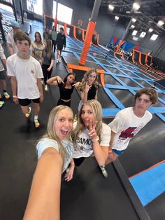 a group of young people standing on top of a blue trampoline course with one pointing at the camera