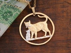 a cat and dog in a circle pendant on a wooden table next to some money