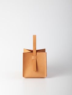 The Cube handbag is a pleasure to carry in your hand or on your wrist. The structural, unique shape offers spacious storage and boasts a hidden clip closure embedded in its handle. The 100% Veg-tanned Vachetta leather bag is intentionally unlined. Crafted with skill by artisans in the Arrhe Studios workshop in Fano, Italy. FIT & SIZING Dimensions: 8 x 8 x 8 in DETAILS Fabric | 100% Veg Tanned Vachetta Italian LeatherColor | NATURALDesigner | ARRHE STUDIOS CARE The leather chosen is subject to ch Minimalist Rectangular Bucket Bag For Office, Minimalist Rectangular Office Bucket Bag, Minimalist Rectangular Bucket Bag With Leather Handles, Minimalist Rectangular Bucket Bag With Removable Pouch, Modern Bucket Box Bag With Leather Handles, Modern Bucket Bag With Top Carry Handle For Gift, Minimalist Bucket Bag With Removable Pouch, Office Rectangular Bucket Bag With Leather Handles, Office Bucket Bag With Leather Handles