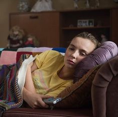 a woman laying on top of a brown couch