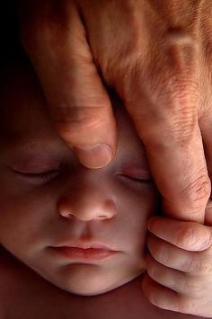 a close up of a person holding a baby's hand over their head and touching it