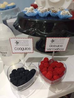 two bowls filled with raspberries and blackberries next to a bottle of water