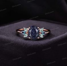 a blue diamond ring on top of a black cloth