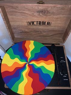 a record player with a wooden case and colorful design on the side, sitting in front of a white wall