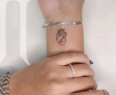 two hands holding each other with a small tattoo on the wrist and an armband