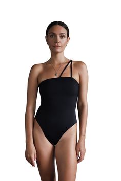 The classy yet minimal Nyra Double String One Piece Swimwear creates an elegant silhouette that flatters all ages, shapes, and sizes. It has two adjustable, skinny straps over the right shoulder which make it effortless to take on and off. Designed with a medium-high leg cut and a full coverage bottom, this suit could easily double as a body suit for everyday wear with a jacket overtop or with a pair of jeans. The lightweight Recycled Nylon Lycra - ECONYL® fabric gently smooths your body, like shapewear. Double lining Full to medium bottom coverage Elastic above the bust for extra support Medium-high leg cut Adjustable, skinny straps over one shoulder UPF50+ technology protects your skin from sun damage Sustainably and ethically made in Bali. Sizes S, M, L, XL. Color black Model wears size Elegant Spring Swimwear With Adjustable Straps, Chic Swimwear With Adjustable Straps, Elegant Swimwear With Asymmetrical Neckline, Elegant Spaghetti Straps Swimwear For Spring, Sleek Swimwear With Adjustable Straps, Elegant Stretch Swimwear With Straps, Chic Second-skin Swimwear With Adjustable Straps, Chic Swimwear With Adjustable Straps For Night Out, Elegant Swimwear With Spaghetti Straps And Bra-friendly Design