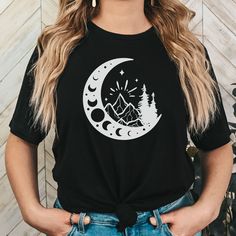 Our moon and mountains shirt is a great gift for anyone! The comfortable fit and cool design of this whimsigoth shirt means that it feels just as good to wear as it is to look at. If you've been looking for a celestial gift for yourself, for Mother's Day, or for your favorite boho friend, you should get this moon phase shirt today. Bella + Canvas brand shirt Unisex Adult Sizing Rolled sleeves in photos are for styling purposes only Props used in photos are not included with the purchase Processing and shipping: Processing time is currently 1-2 weeks Standard shipping: usually 2-5 business days after processing time Returns and exchanges: I hope you will love your product! Due to the made-to-order nature of this shop, I am unable to accept returns and exchanges. Be sure to check the sizing Black Short Sleeve Shirt With Moon Print, Black Crew Neck Top With Sun And Moon Design, Whimsigoth Shirt, Moon And Mountains, Mountains Shirt, Moon Phases Shirt, Celestial Gifts, Vintage Moon, Mountain Shirt