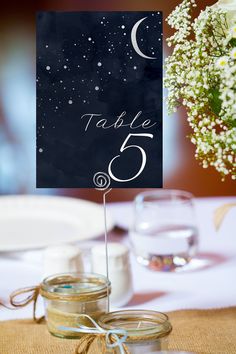 the table numbers are placed on top of jars with baby's breath in them