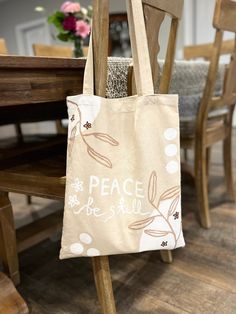 a tote bag sitting on top of a wooden chair in front of a table