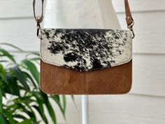 This gorgeous bag is crafted in 100% Genuine Cowhide and natural cow print. The bag features real calf leather back and adjustable crossbody strap. Inside is cloth lined with 3 open pockets and 1 zip pocket. The strap is detachable to covert into a clutch or make up bag to be tossed into a larger bag Size: 8.75 Inches x 6.5 Inches Light weight design; can be comfortably carried all day Durable real cowhide- low maintenance Easy to clean Recycled Leather Bag, Cow Print Leather Bag For Daily Use, Leather Cow Print Bag For Everyday Use, Brown Cow Print Bag For Everyday Use, Brown Cow Print Bag, Western Bags Purses, Western Bags, Printed Leather Bag, Western Bag