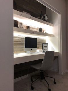 a desk with a computer monitor and keyboard on it in front of a white wall