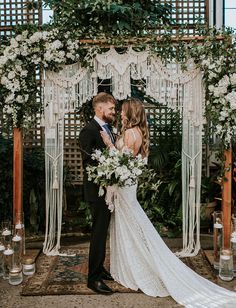 a bride and groom standing in front of an outdoor wedding ceremony arch with white flowers