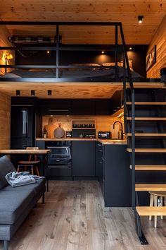 a living room and kitchen with stairs leading up to the loft bed in this modern cabin