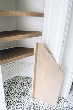 a wooden shelf sitting on top of a tiled floor