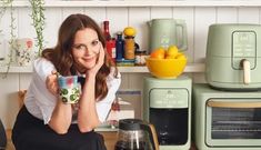 a woman sitting on a kitchen counter holding a cup