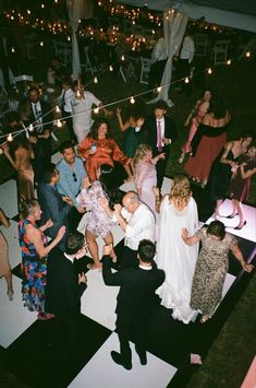 a group of people standing on top of a white floor next to each other at a party