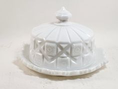 a white ceramic covered dish on a white surface