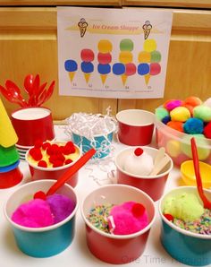 ice cream shoppe has many different types of desserts on the table, including cupcakes